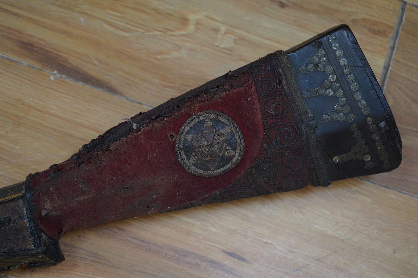 An Indian axe bhuj, with broad curved blade, iron haft with elephant head top, all covered over with silver gilt foil engraved with flower heads, the pommel unscrews to reveal a stiletto, with its copper mounted sheath,